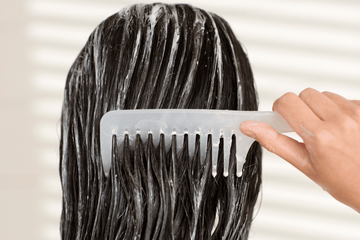 woman combing conditioner though her hair