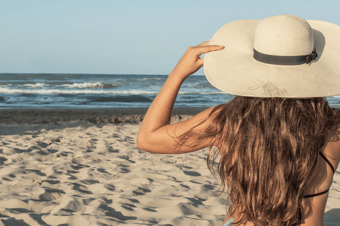 Woman on beach wearing hat with wind blowing through her hair