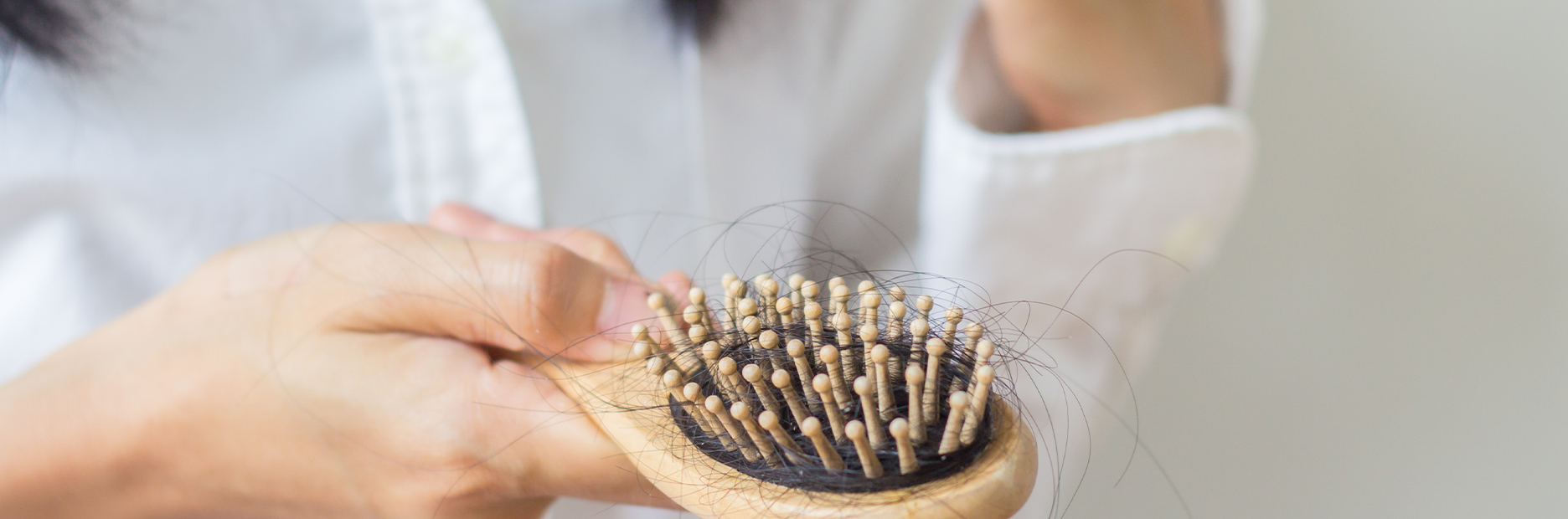 FFOR Hair banner image of woman holding hair brush with strands of hair tangled in brush